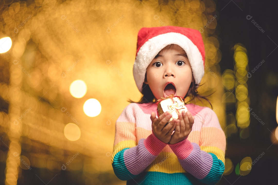 Criança feliz no chapéu vermelho de Papai Noel segurando presentes de Natal