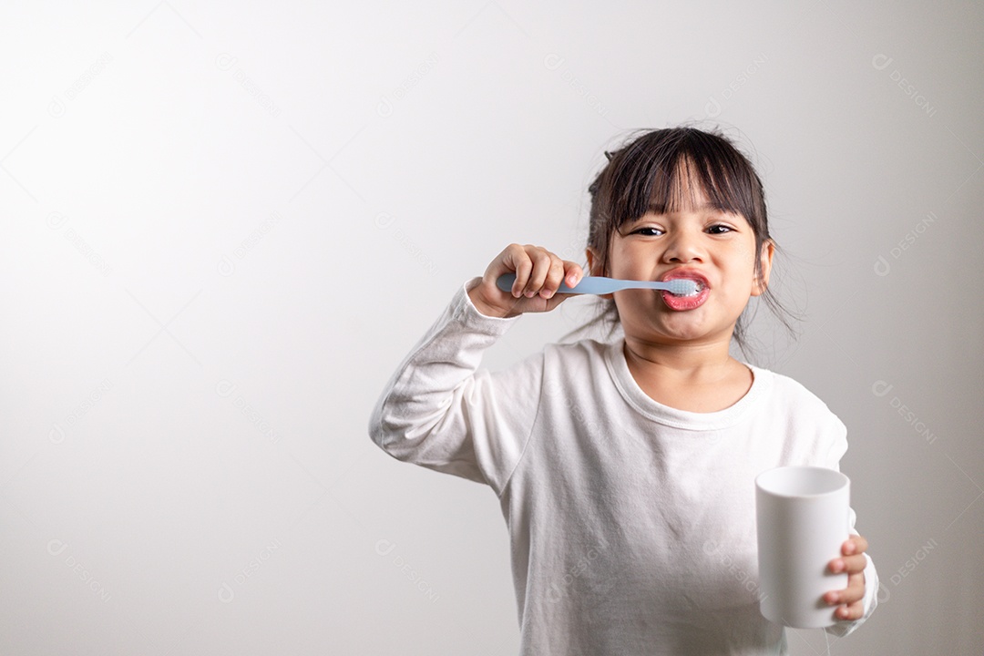 Menina linda criança escovando os dentes no fundo branco