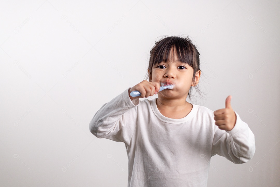 Menina linda criança escovando os dentes no fundo branco