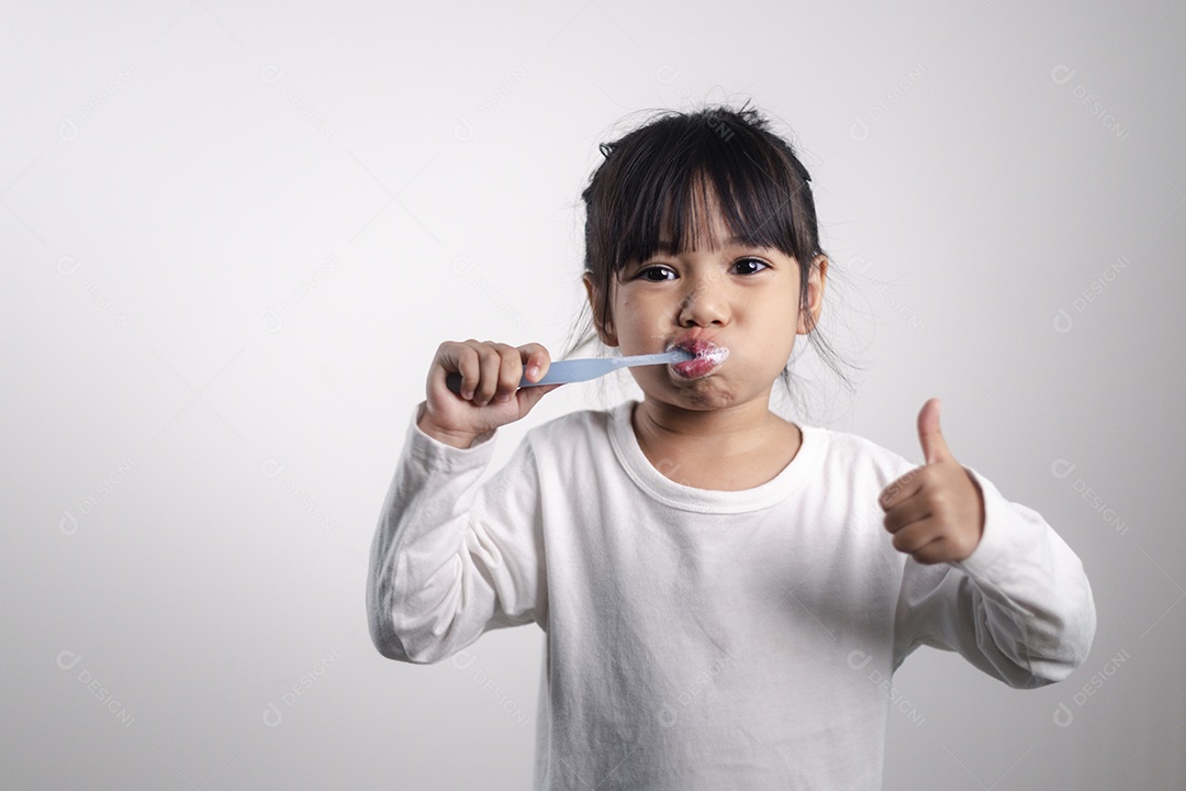 Menina linda criança escovando os dentes no fundo branco