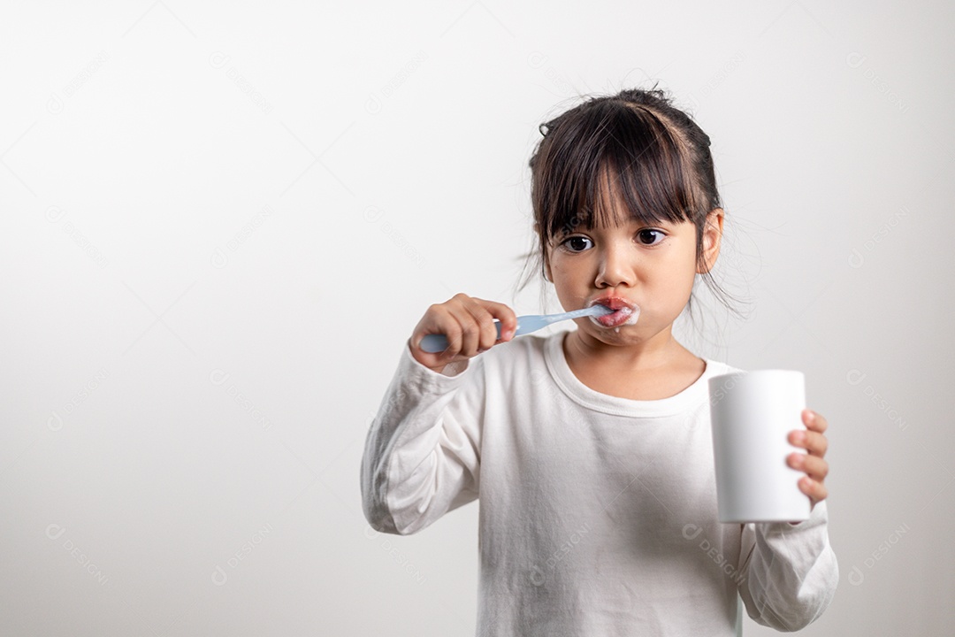Menina linda criança escovando os dentes no fundo branco