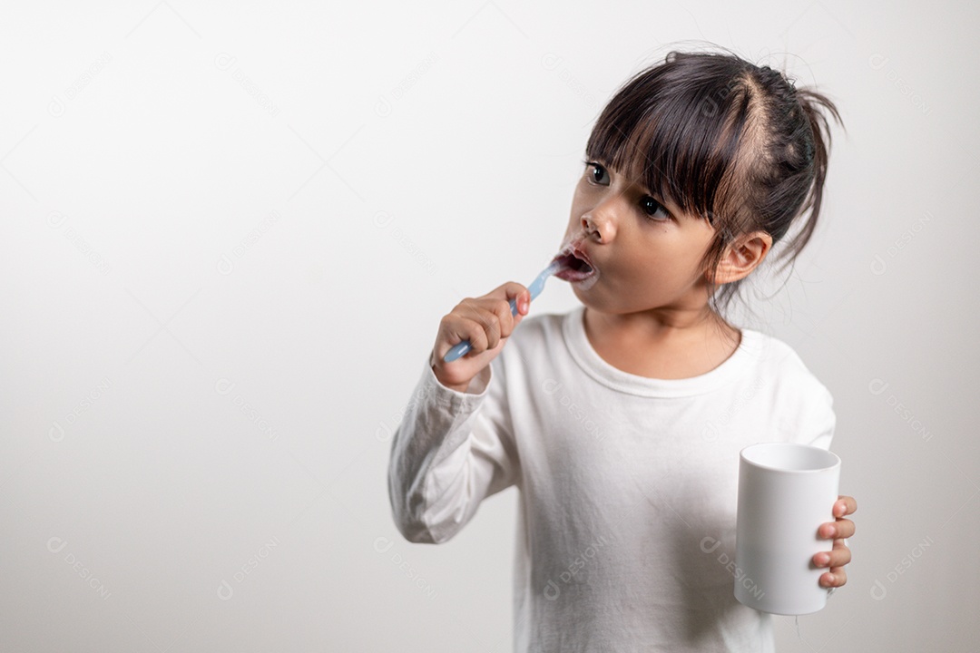 Menina linda criança escovando os dentes no fundo branco