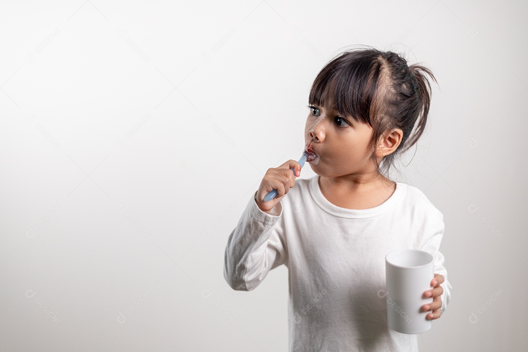 Menina linda criança escovando os dentes no fundo branco