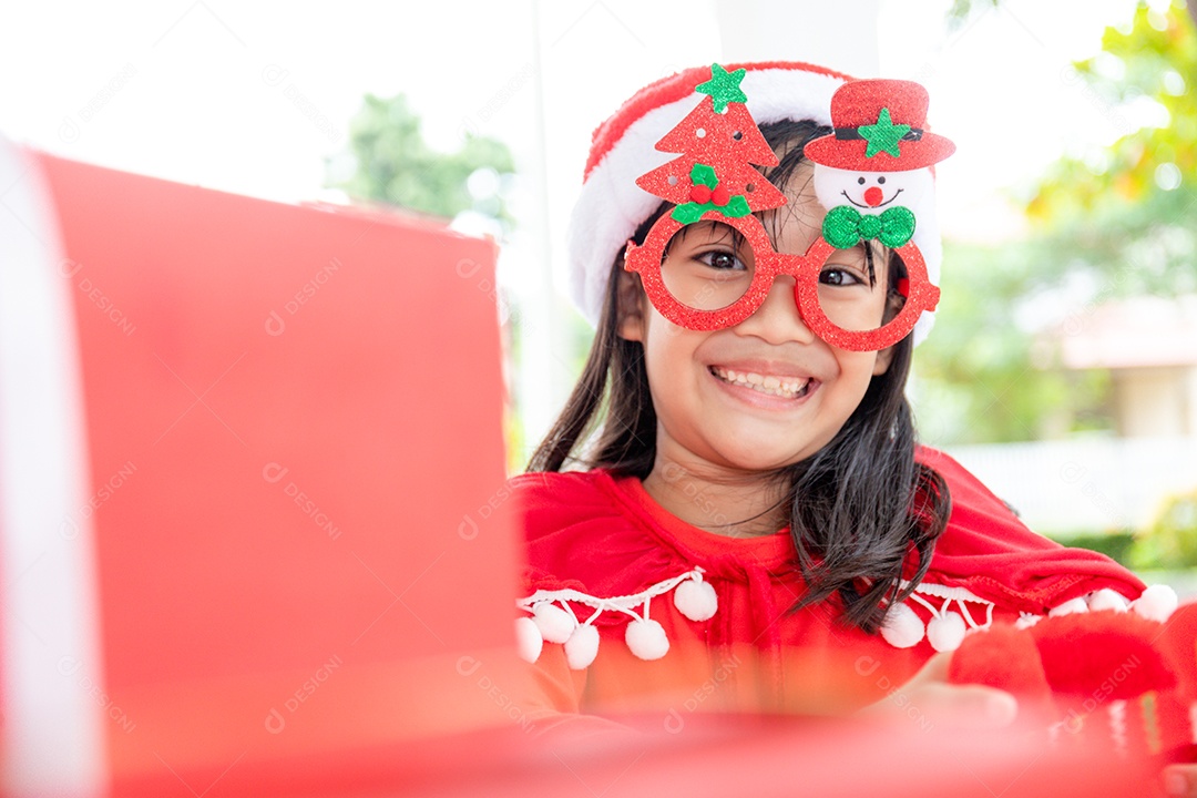 Menina asiática no chapéu de Papai Noel vermelho sobre fundo branco.