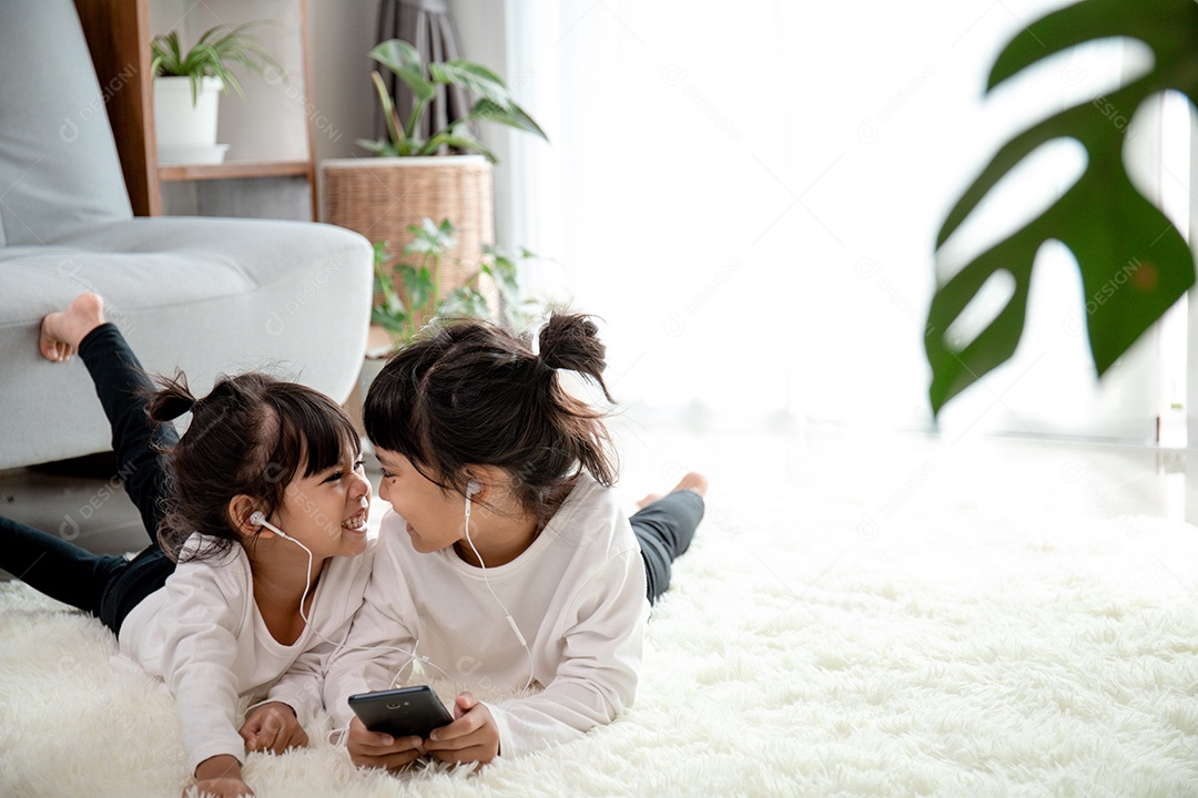 Irmãos asiáticos juntos no chão usando smartphone