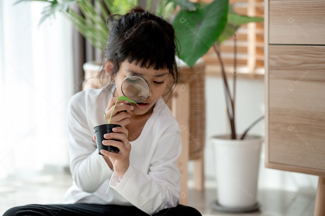 Menina concentrada com lupa examinando a planta verde