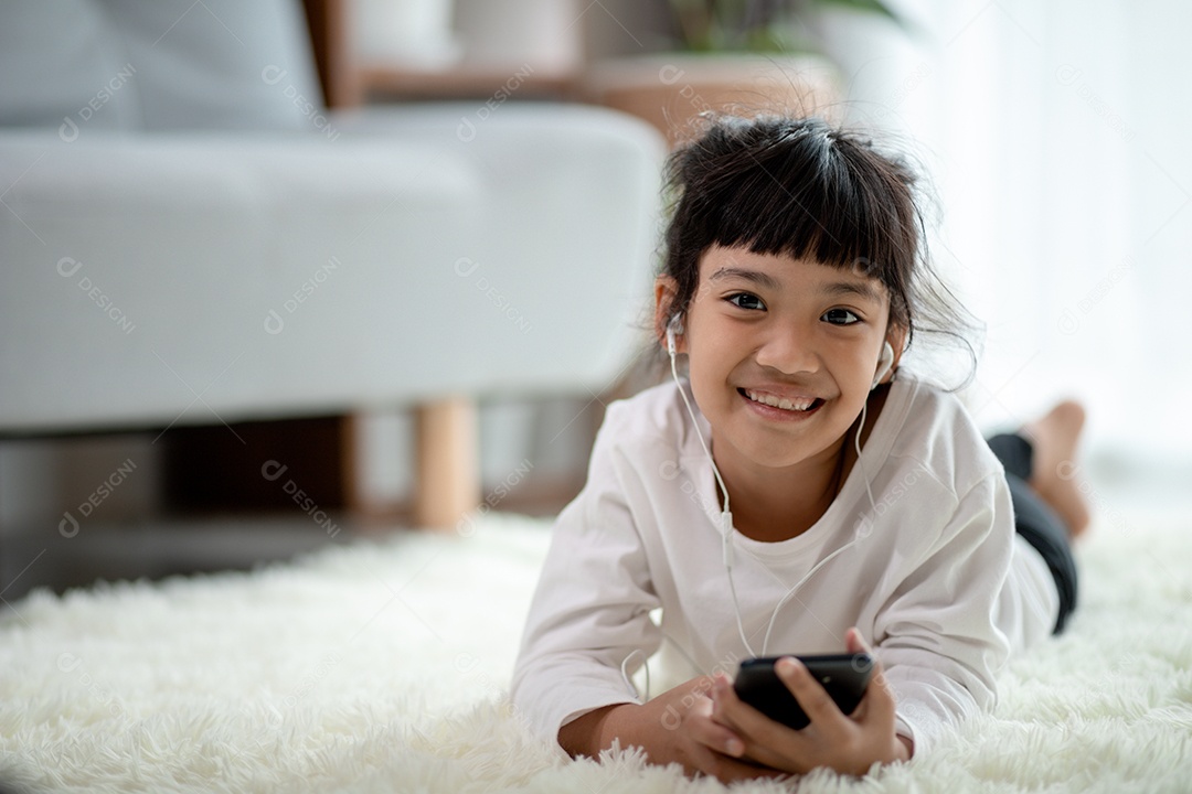 Menina muito asiática usando fones de ouvido para ouvir música por smartphone