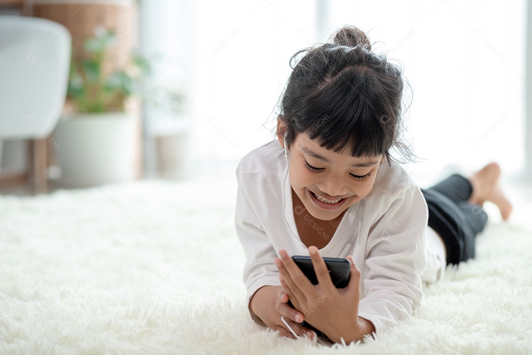 Menina muito asiática usando fones de ouvido para ouvir música por smartphone