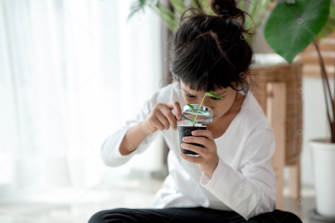 Menina concentrada com lupa examinando a planta verde