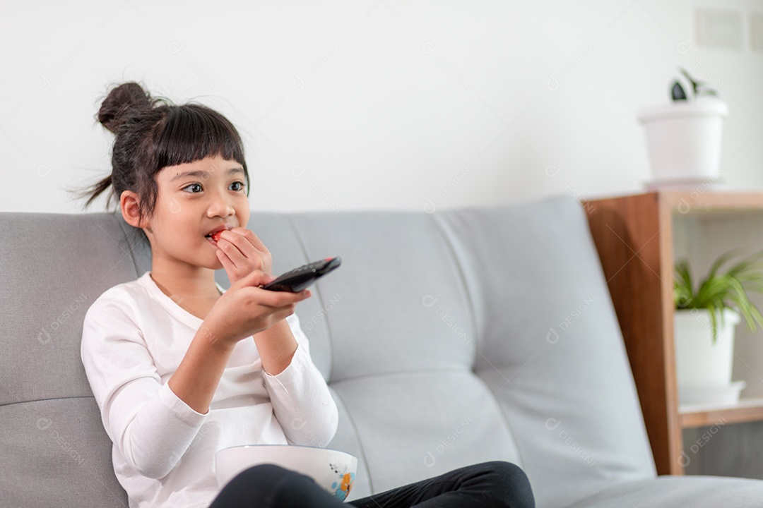 Garota com controle remoto sentado no sofá assistindo a um filme na tv