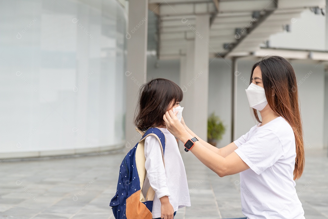 Mãe asiática ajuda sua filha usando uma máscara médica para proteção