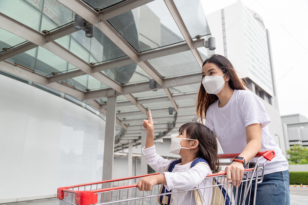 Mãe asiática ajuda sua filha usando uma máscara médica para proteção