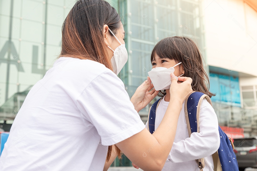 Asian mother helps her daughter wearing a medical mask for protection