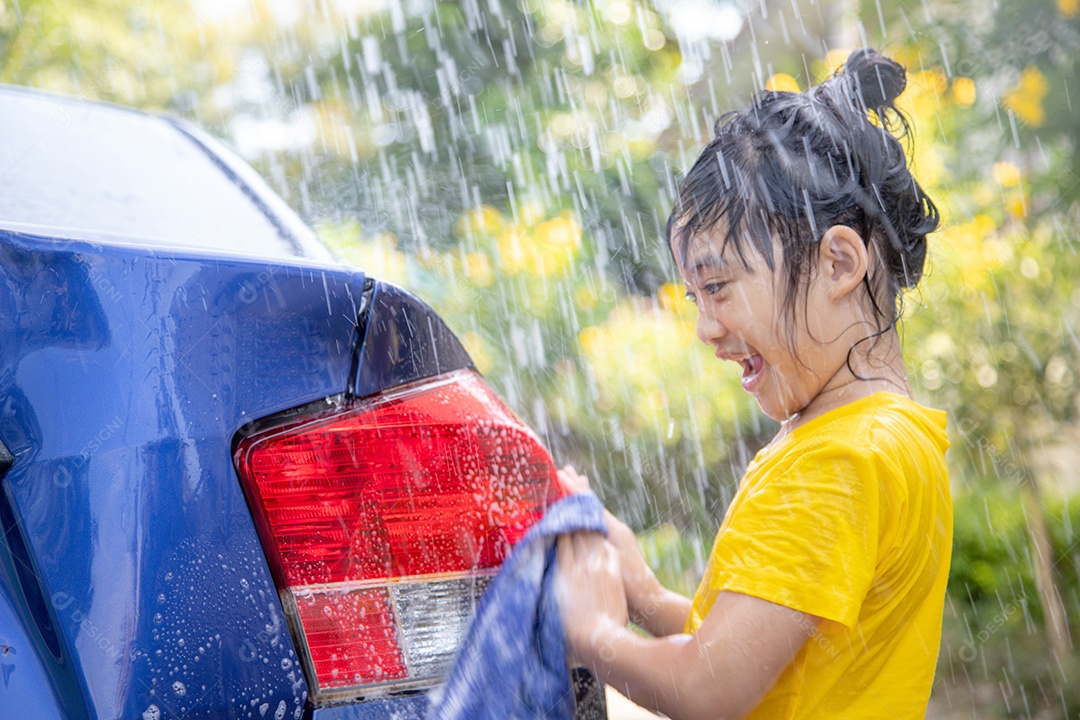 Menina asiática feliz lavando carro em salpicos de água e luz solar