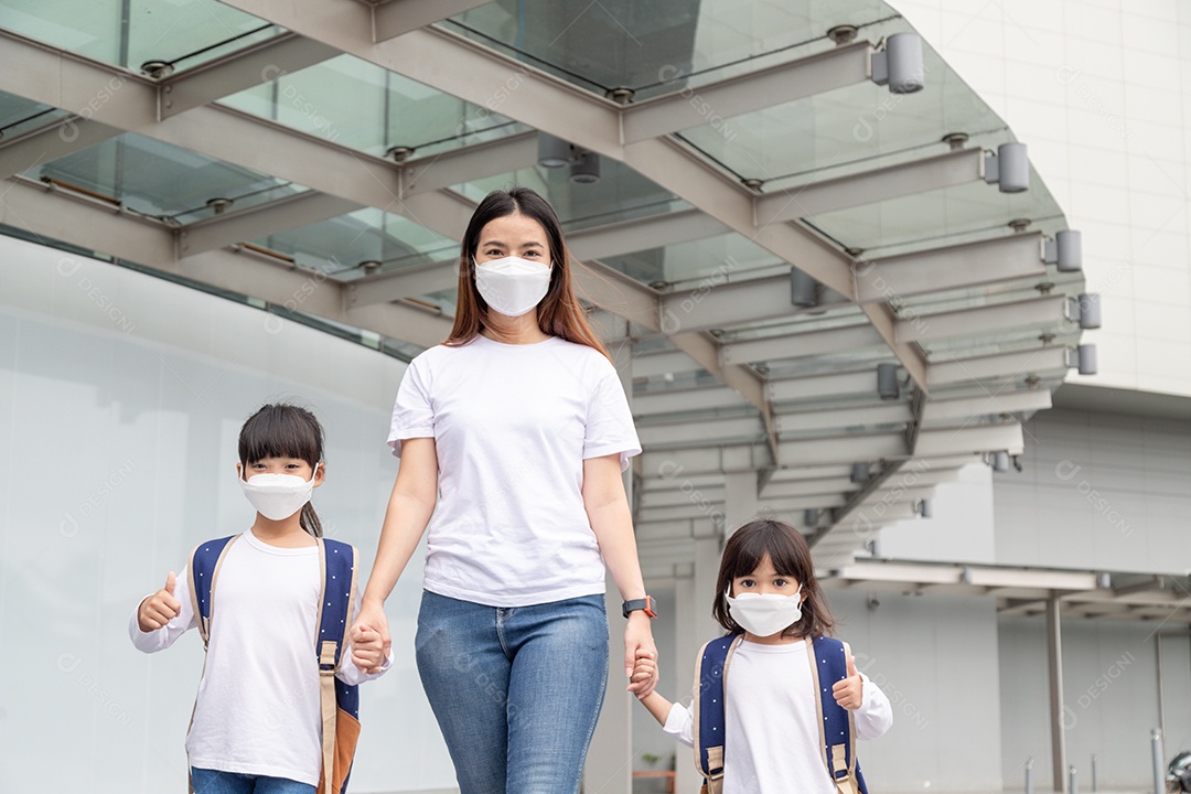 Mãe asiática ajuda sua filha usando uma máscara médica para proteção