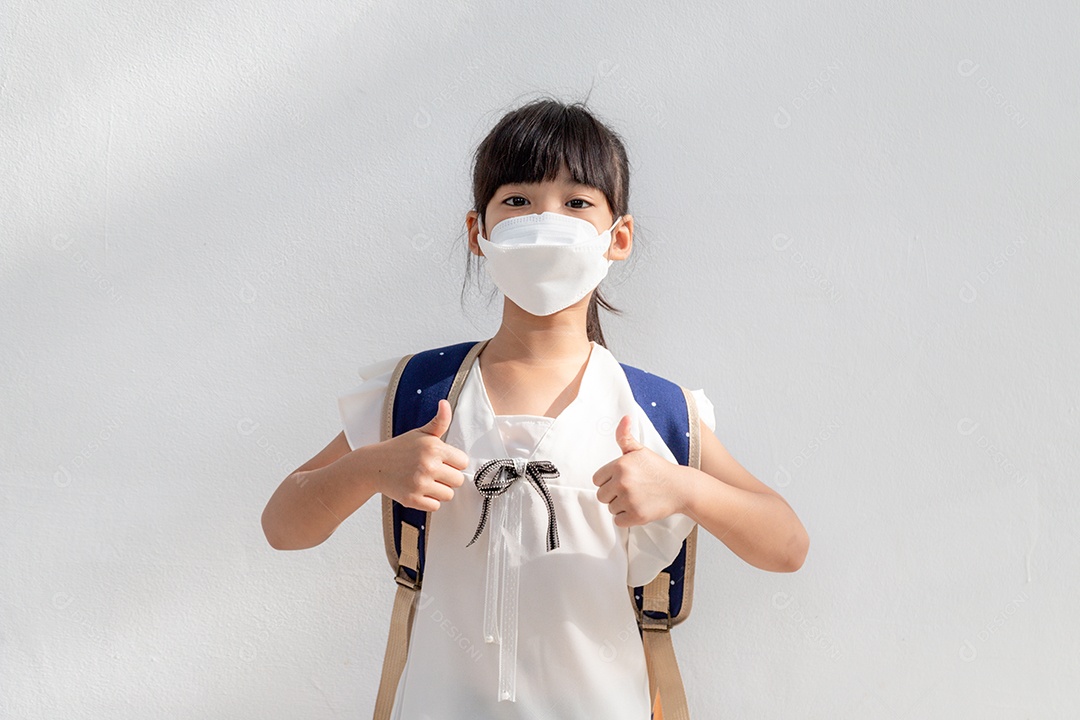 Menina asiática usando máscara para proteger e mostrar os polegares