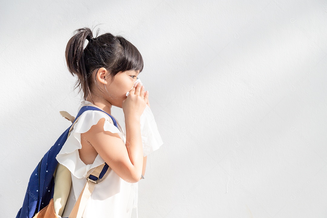 Menina asiática doente com espirros no nariz e tosse fria