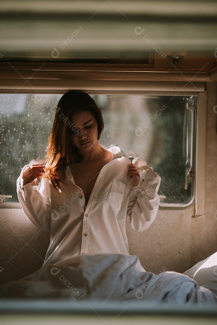 Mulher jovem e bonita em uma camisa branca no quarto em casa