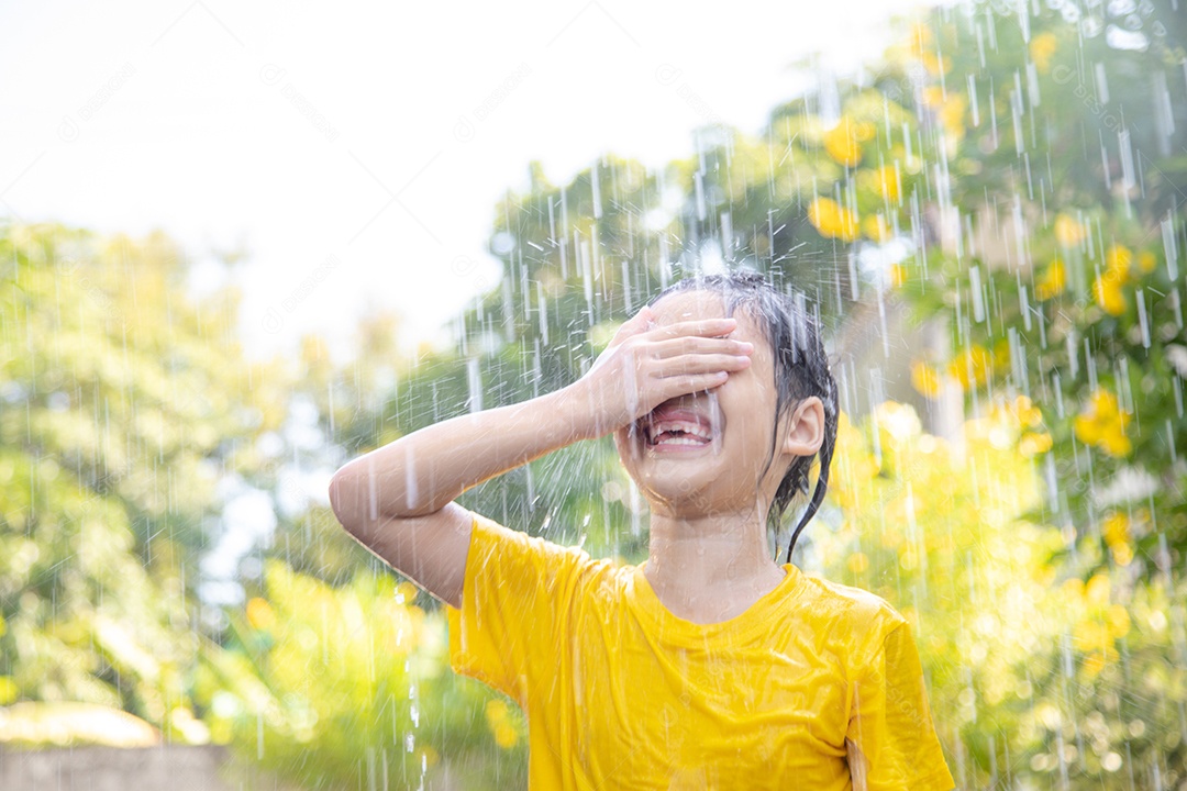 Menina asiática feliz lavando carro em salpicos de água e luz solar em casa