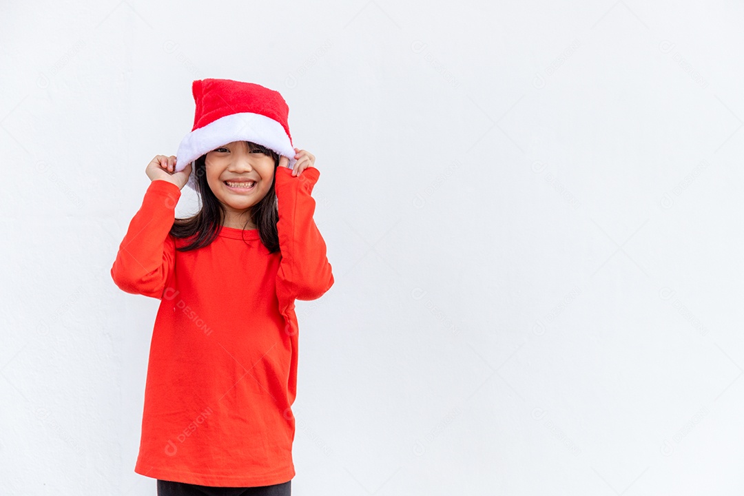 Menina asiática no chapéu de Papai Noel vermelho sobre fundo branco.