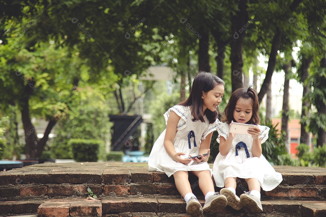 Crianças de conceito e gadgets. Duas irmãs meninas olham