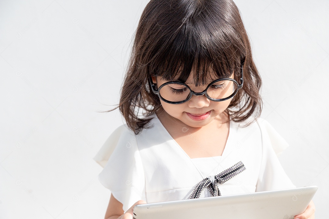 Uma garotinha está concentrada no telefone, olhe para o smartphone