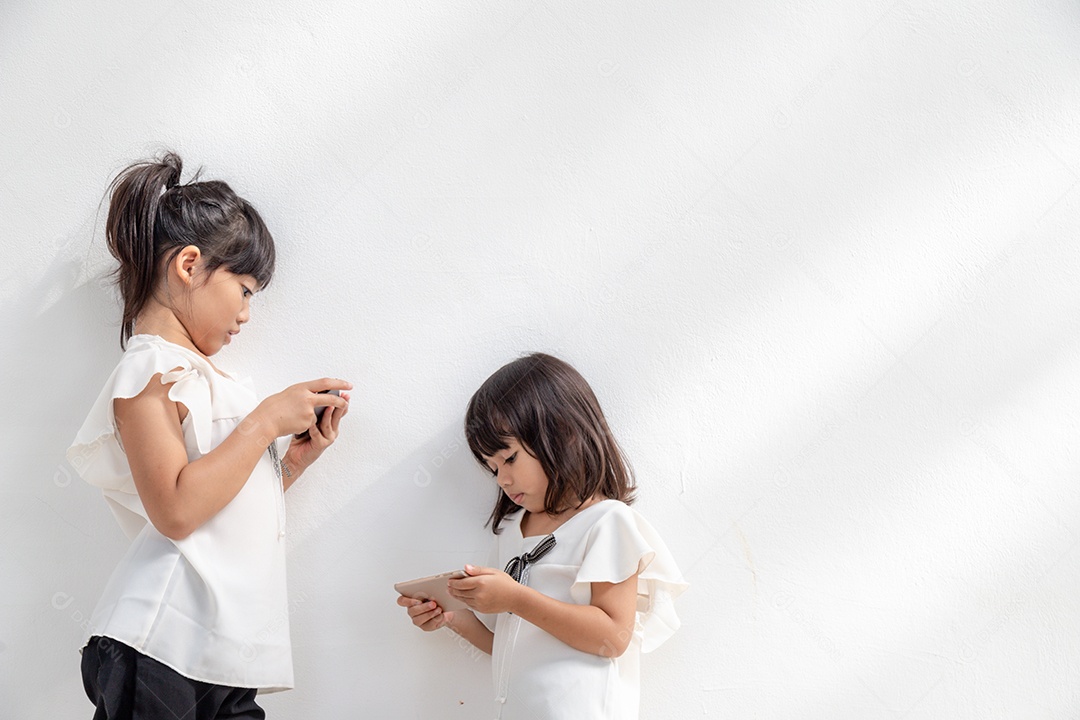 Meninas do irmão assistindo seus smartphones em fundo branco. Então