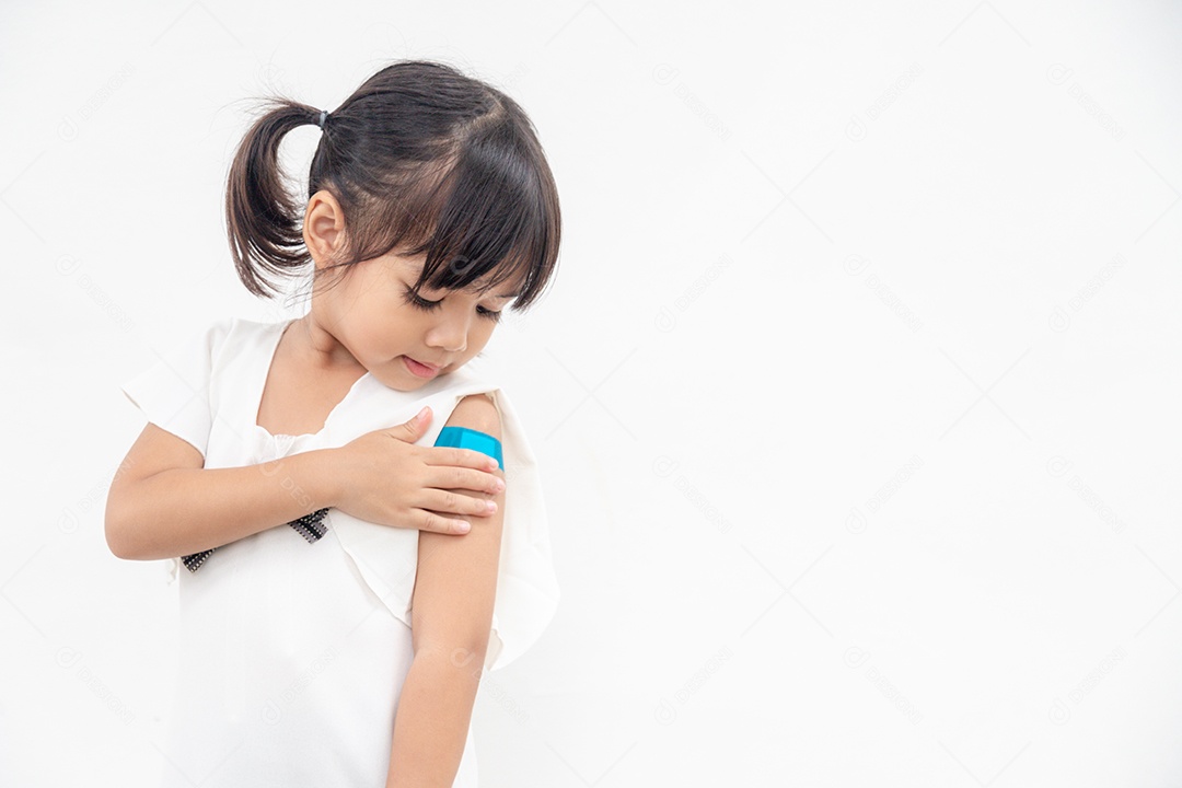 Menina asiática mostrando o braço depois de ser vacinada ou inoculada