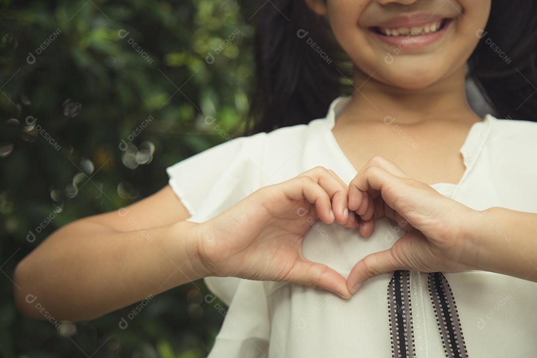 Mãos de menina fazendo uma forma de coração no fundo branco