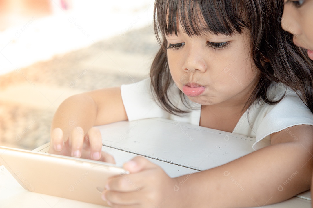 Garotinha está concentrada no tablet, olhe para o tablet,