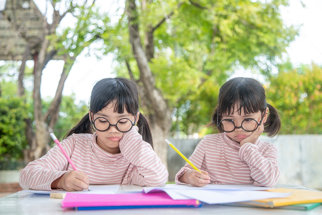 Duas crianças asiáticas fazendo lição de casa juntos em casa
