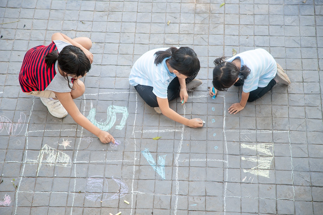 Crianças asiáticas brincam ao ar livre. A menina da criança desenha