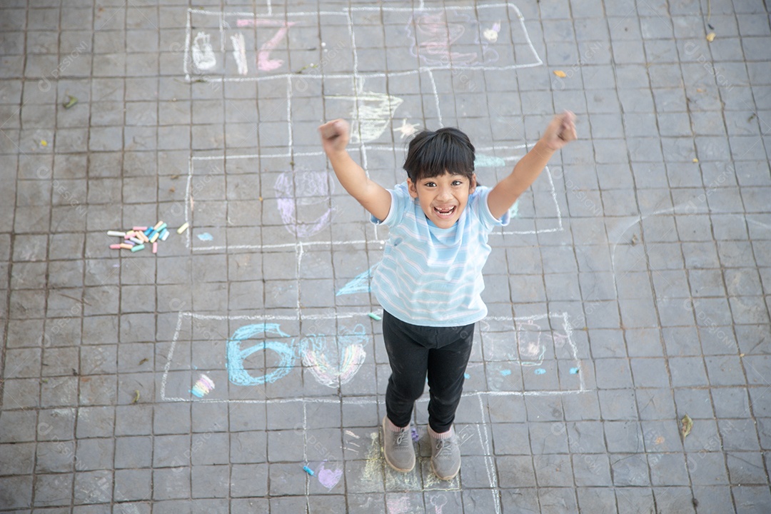Criança asiática brincam ao ar livre. A menina da criança desenha