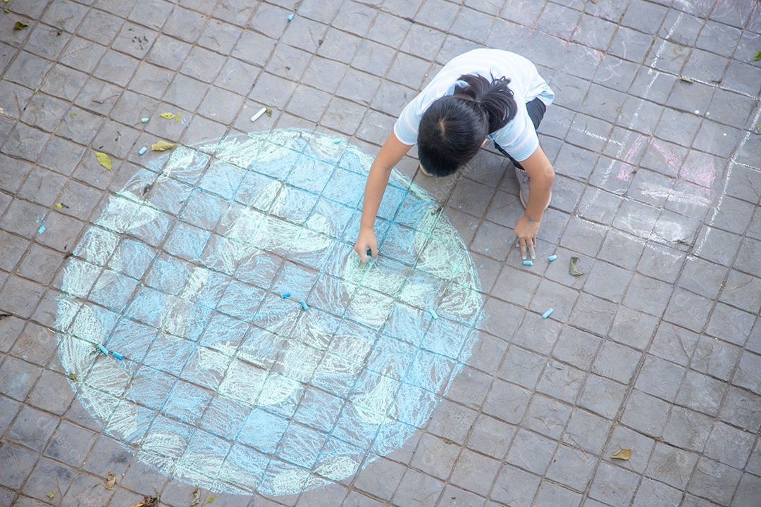Criança asiáticas brincam ao ar livre. A menina da criança desenha um wi do globo do planeta