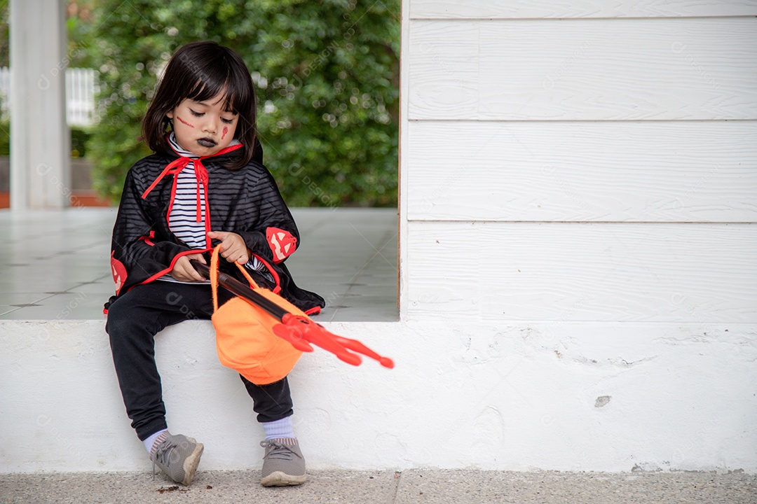 Menina asiática em fantasia de demônio segurando tridente preto e vermelho