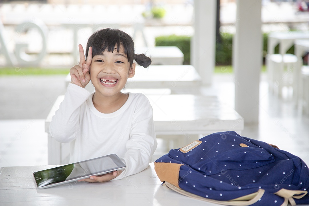 menina feliz usando um tablet em casa, sorrindo bonito pré-escolar