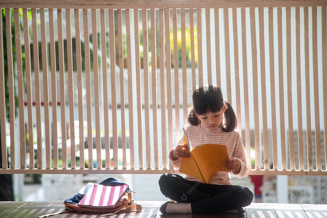 Linda garota asiática lendo um livro em casa