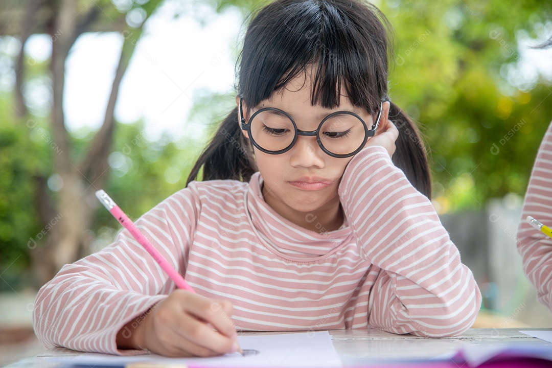 Menina asiática escrevendo livro em sala de aula