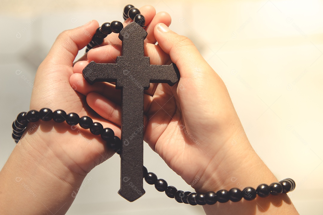 Menina asiática rezando segurando a cruz, conceito cristão.