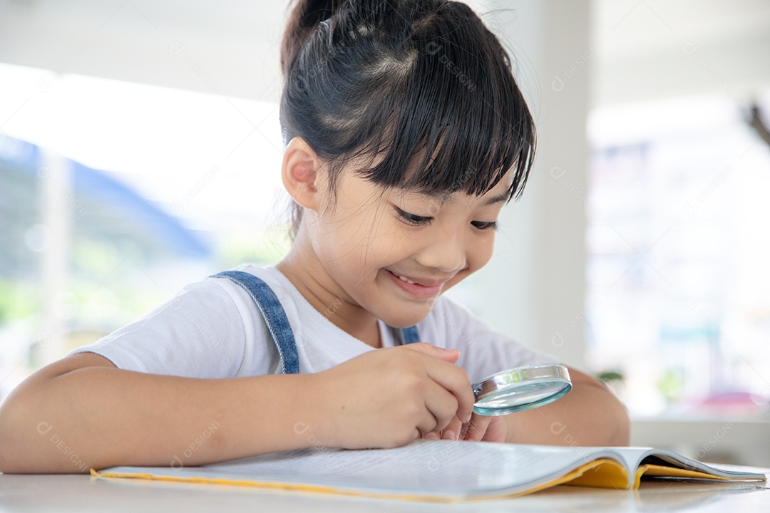 Asian girl reading the books on the table with a magnifying glass