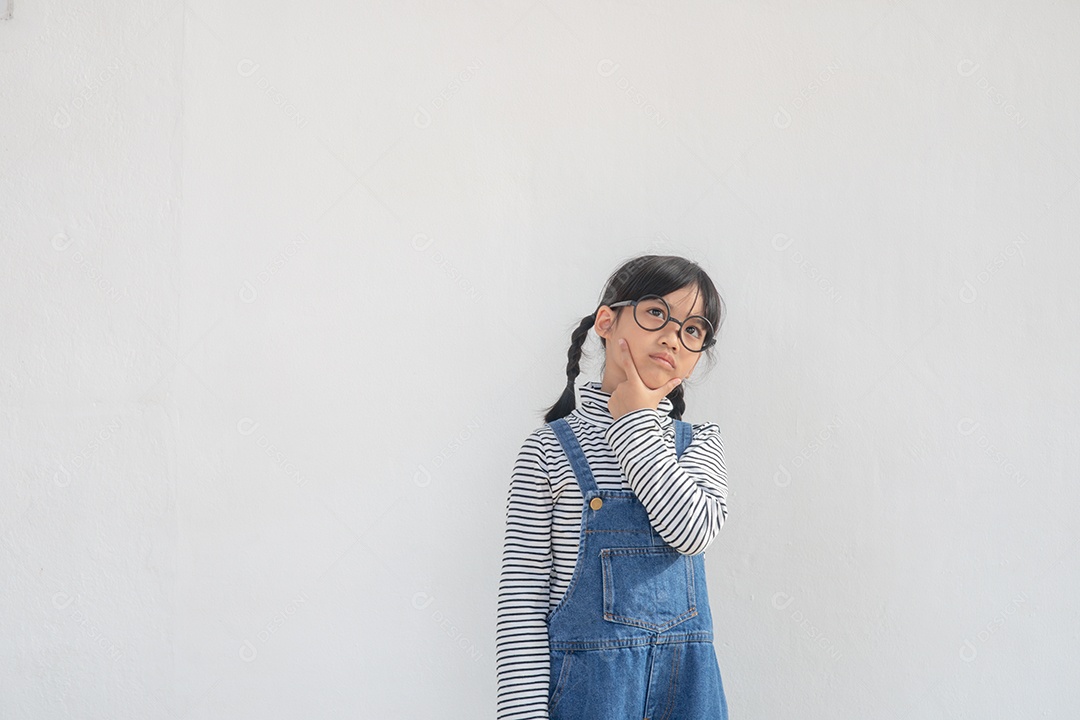 Linda garotinha asiática usando óculos e pensando