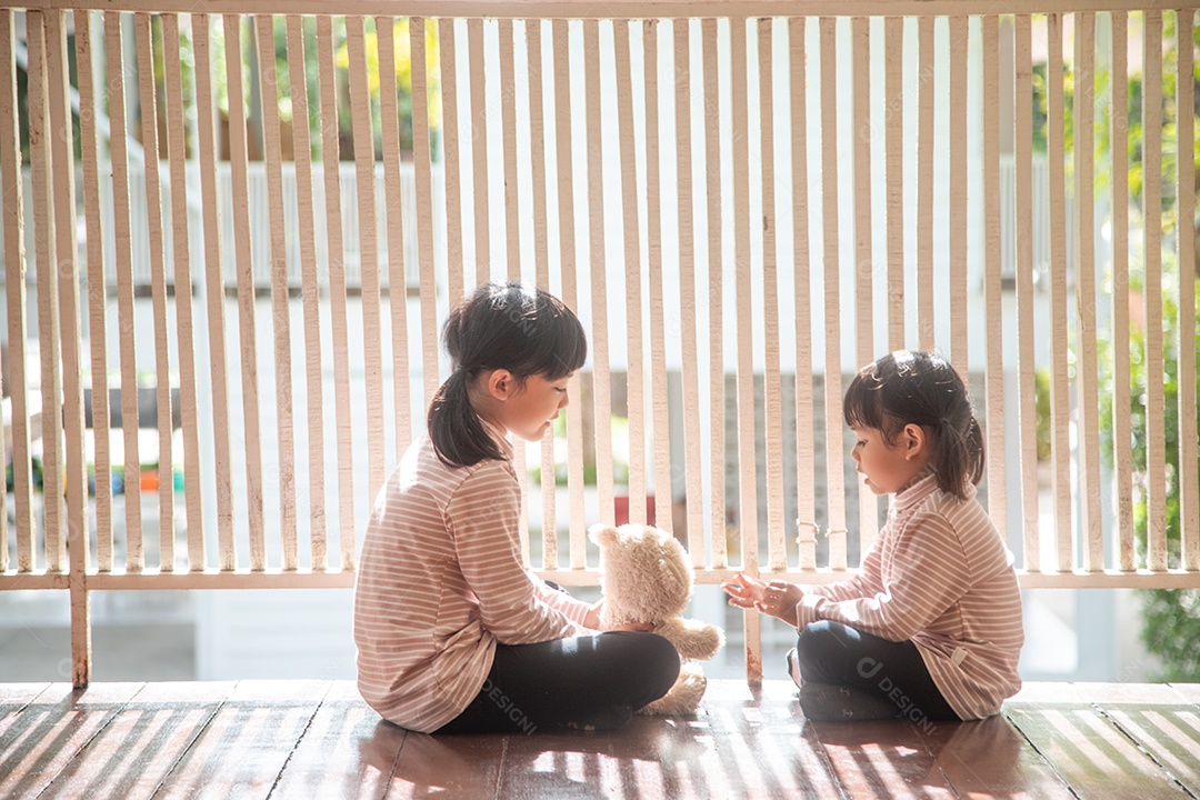 irmãos menina asiática brincando com ursinho de pelúcia