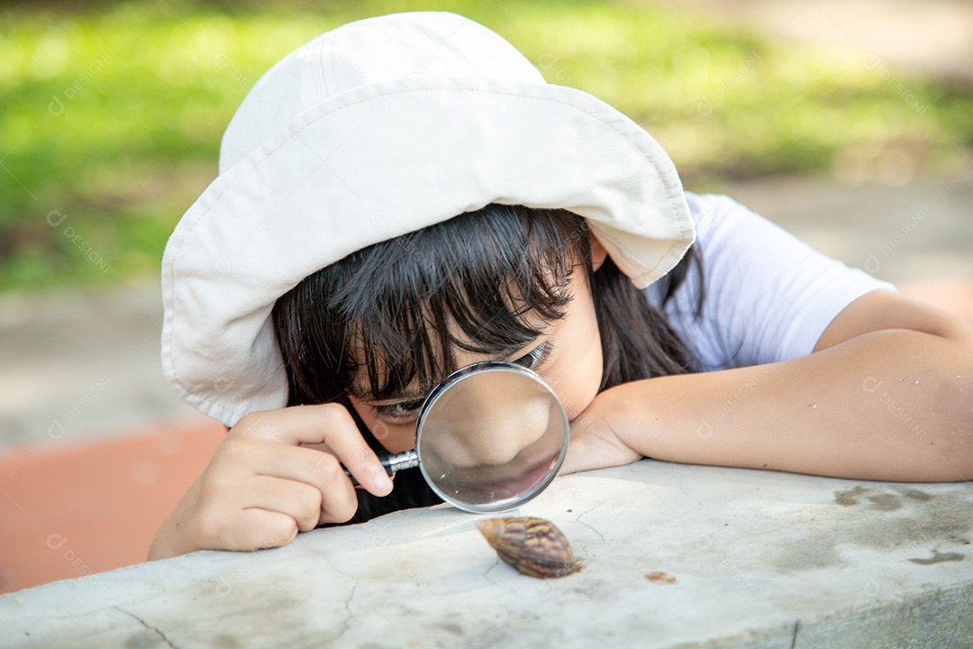 Garota criança feliz explorando a natureza com uma lupa