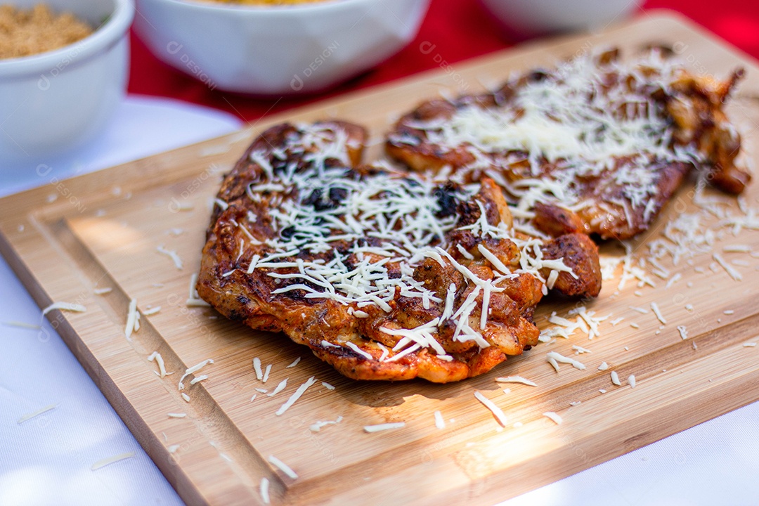 Carne assada costela com queijo ralado sobre uma tabua de madeira