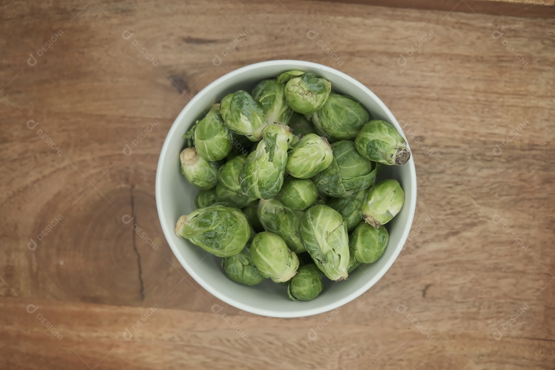 Couves de Bruxelas em tigela branca na mesa de madeira.