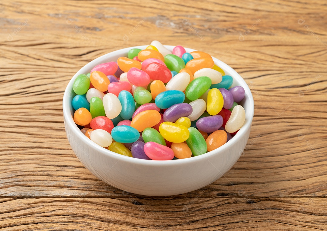 Jujubas coloridas em uma tigela sobre a mesa de madeira.