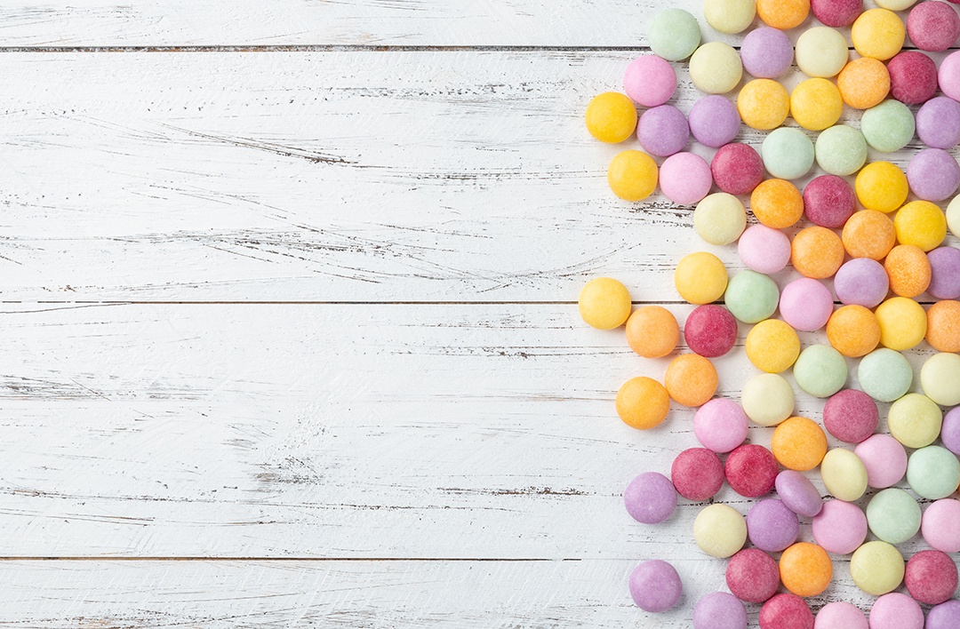 Doces coloridos sobre mesa de madeira com espaço de cópia.