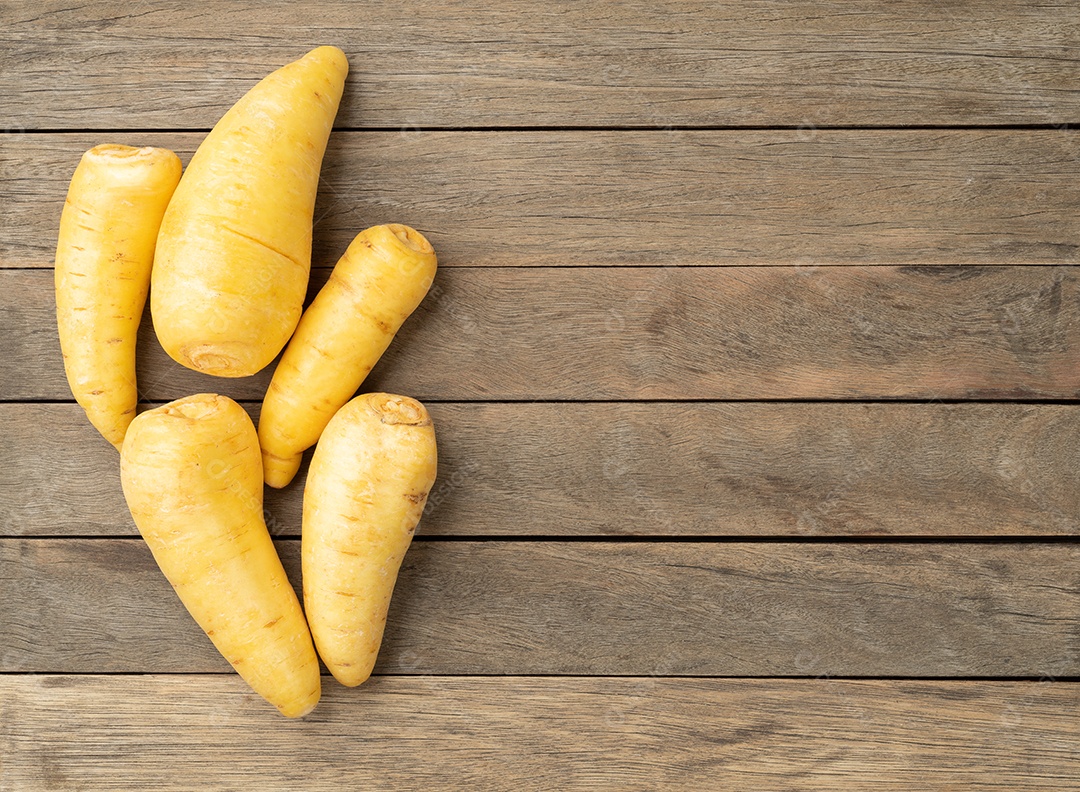 Mandioquinha crua ou arracacha sobre mesa de madeira com espaço de cópia.