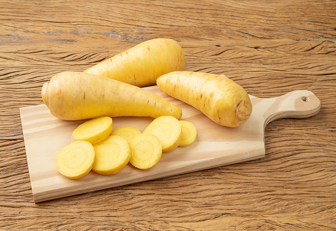 Mandioquinha crua ou arracacha cortada sobre tabua de madeira.