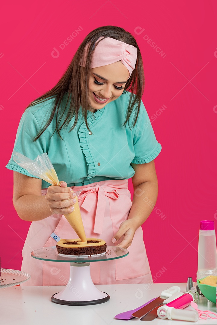 Linda mulher jovem chefe de cozinha preparando bolo